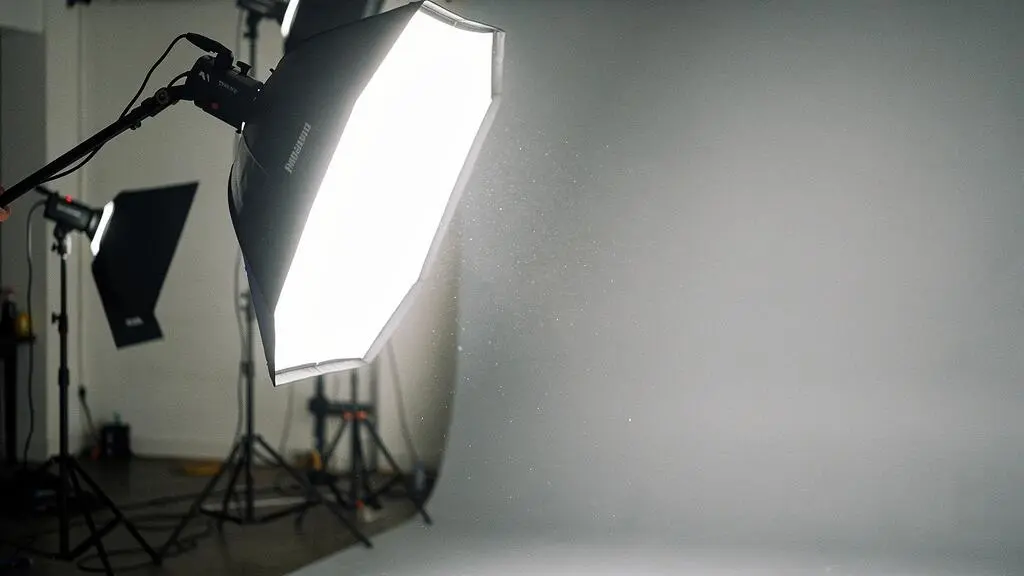 Photographe ajustant un softbox de studio pour sculpter la lumière sur un sujet, illustrant la maîtrise de l'éclairage professionnel