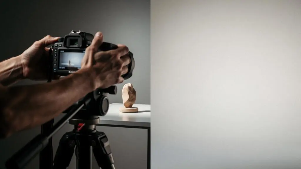 Photographe professionnel ajustant le cadrage d'une prise de vue produit selon la règle des tiers dans un studio lumineux